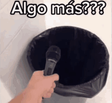 a person is holding a microphone in front of a trash can that says algo mas on it