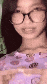 a young girl wearing glasses and a purple shirt is smiling .