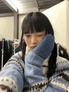 a girl wearing a blue sweater and blue mittens is taking a selfie