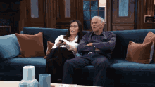 a man and a woman are sitting on a blue couch watching television