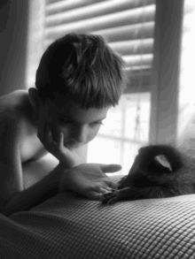 a black and white photo of a boy looking at a raccoon