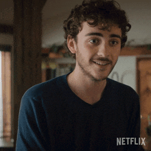 a man with curly hair and a beard is wearing a blue shirt with netflix written on it