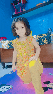 a little girl is kneeling down on a mickey mouse rug