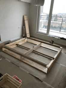 a wooden frame is being built in a room with a large window