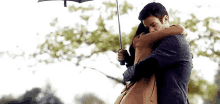 a man is holding an umbrella and hugging a woman .