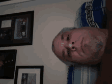 a man laying on a blue and white blanket with framed pictures behind him