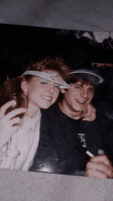 a man and a woman are posing for a picture and the woman is wearing a hat that says playing cards on it