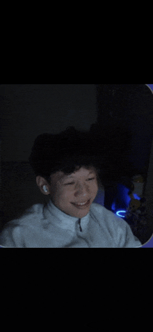 a young man wearing ear buds is smiling in a dark room