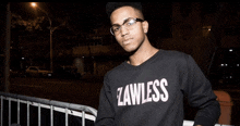 a young man wearing glasses and a black sweater that says lawless