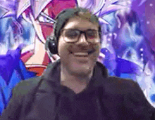 a man wearing headphones and glasses is smiling in front of a painting .