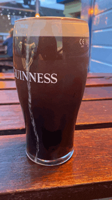 a glass of guinness is sitting on a wooden table