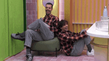 two men are sitting on a couch and laughing together