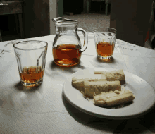 a pitcher of tea sits on a table next to a plate of bread