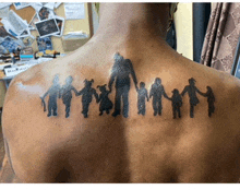 a man has a tattoo of a family on his back