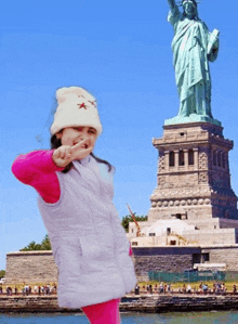 a little girl stands in front of the statue of liberty in new york city