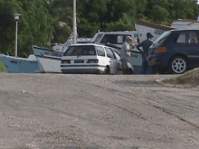 a white car is parked in front of a boat that says os7 on the side