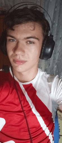 a young man wearing headphones and a red and white shirt takes a selfie