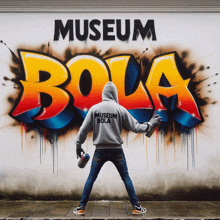 a man standing in front of a wall that says museum bola on it