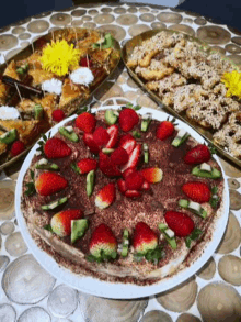 a pizza with strawberries and kiwi on it is on a plate on a wooden table .