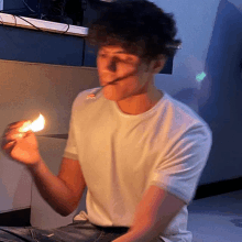 a man in a white t-shirt is lighting a match