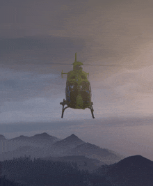 a green helicopter is flying over a mountain landscape