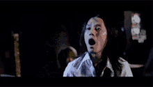 a man with long hair is screaming in a dark room