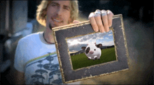 a man is holding a picture frame with a picture of a cow on it