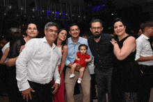 a group of people posing for a picture with one of them holding a baby