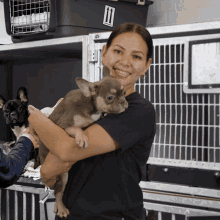 a woman in a black shirt holds a puppy in her arms in front of a black box with the number 11 on it