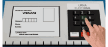 a person pressing a button on a urna eleitoral device