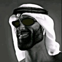 a black and white photo of a man wearing sunglasses and a white head scarf .