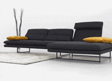 a black sectional couch with a yellow pillow on it