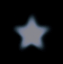 a white star is glowing in the dark on a black background .