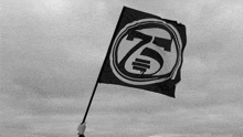 a black and white photo of a person holding a flag with a k on it