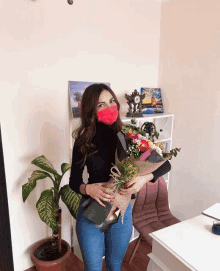 a woman wearing a red face mask holds a bouquet of flowers