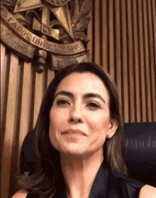 a woman is smiling in front of a wooden wall with the words estados unidos do brasil written on it