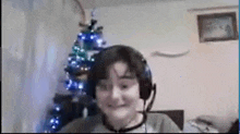 a young boy wearing headphones and a microphone is sitting in front of a christmas tree .