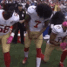 a group of football players are kneeling on the field and one of them has the number 7 on his jersey .