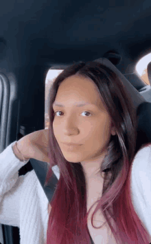 a woman with red hair and a nose ring is sitting in a car