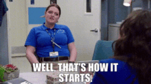 a woman in a blue shirt is sitting at a table talking to another woman in a hospital room .