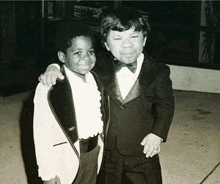 a black and white photo of two boys in tuxedos posing for a picture