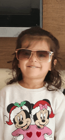 a little girl wearing sunglasses and a minnie mouse sweatshirt