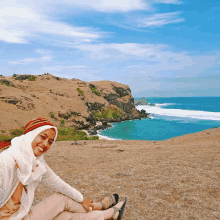 a woman sitting on a hill overlooking the ocean