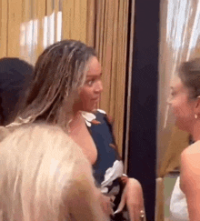 a group of women are standing next to each other in a room and talking .