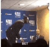 a man in a suit is standing in front of a wall with a sign that says nba finals on it .