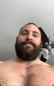 a shirtless man with a beard is taking a selfie