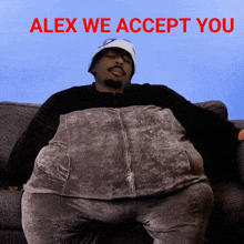 a man sitting on a couch with a pillow on his stomach and the words alex we accept you