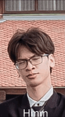 a man wearing glasses and a suit is making a funny face in front of a brick building .