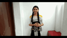 a girl with long braids is standing in front of a wall