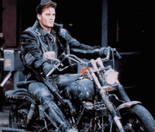 a man in a leather jacket is riding a motorcycle in front of a building